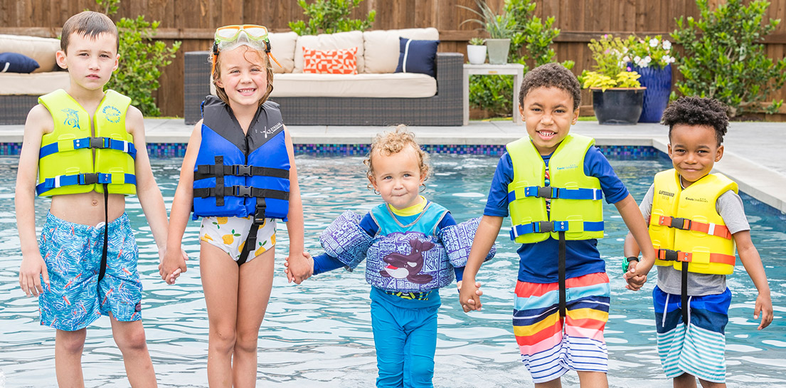 Children standing in pool with life jackets