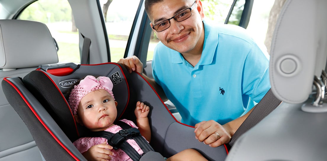 Father setting up car seat for daughter